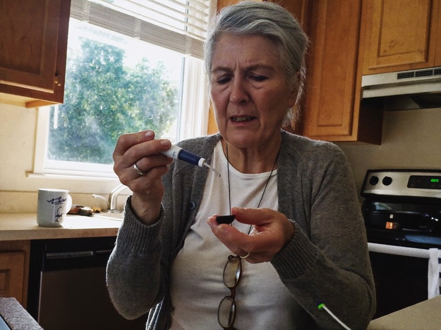 Woman checking her morning blood sugar in her kitchen