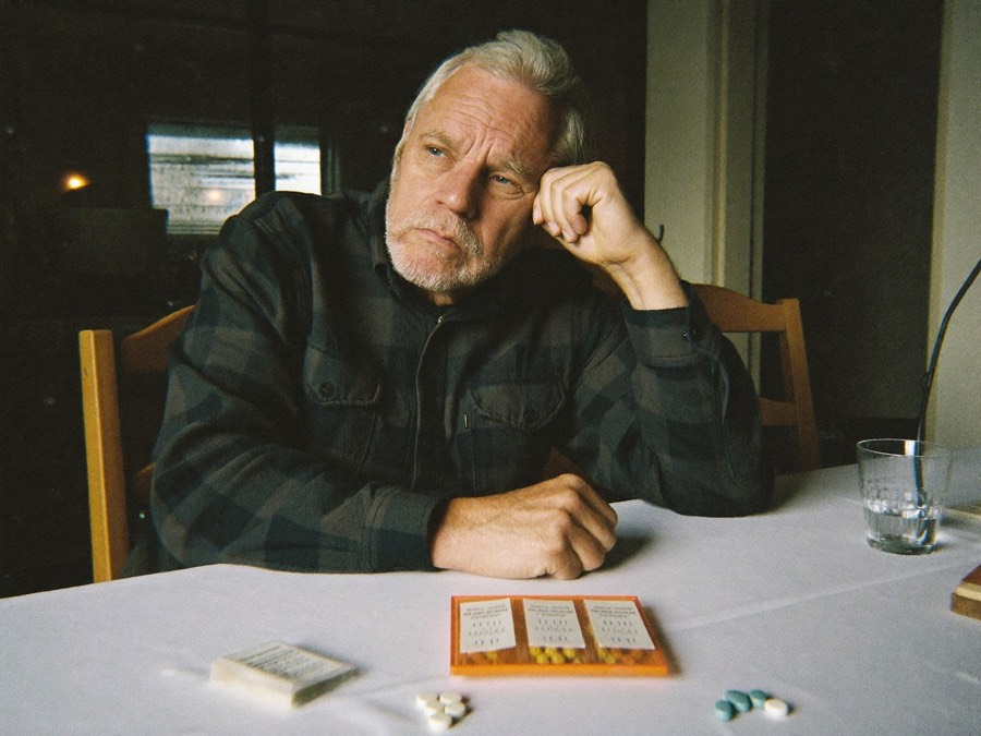 Man reviewing his daily pill organizer at the kitchen table